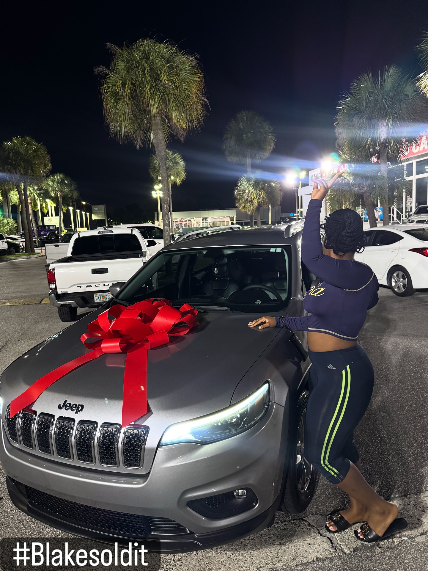 Client celebrating next to her new Jeep Cherokee with a red bow on the hood